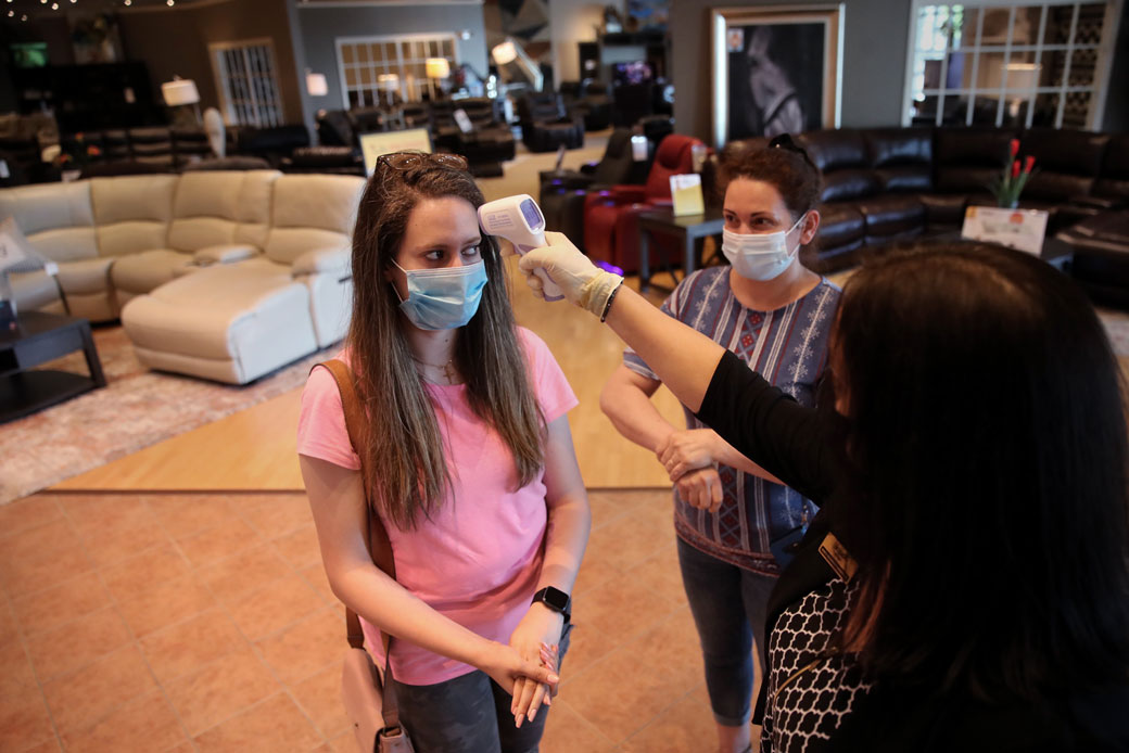 A mother watches her daughter have her temperature taken as the two shop for furniture in Nashua, New Hampshire, on June 2, 2020. (Getty/The Boston Globe/Craig F. Walker)