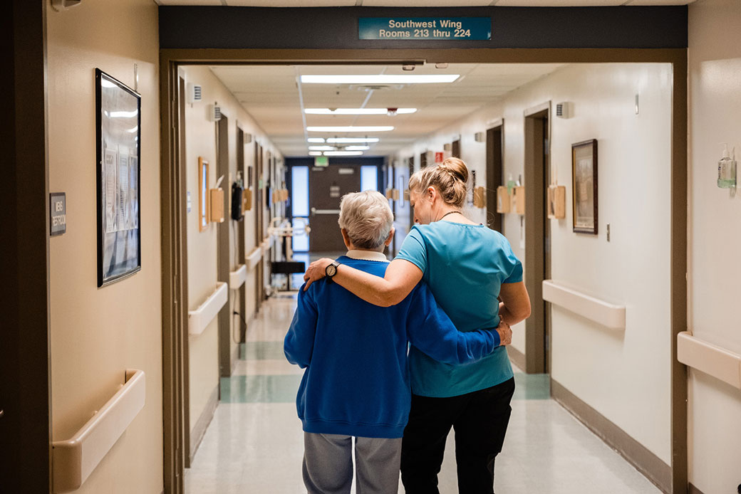 A registered nurse walks a resident back to her room at an assisted living center in Dayton, Washington, March 2020.