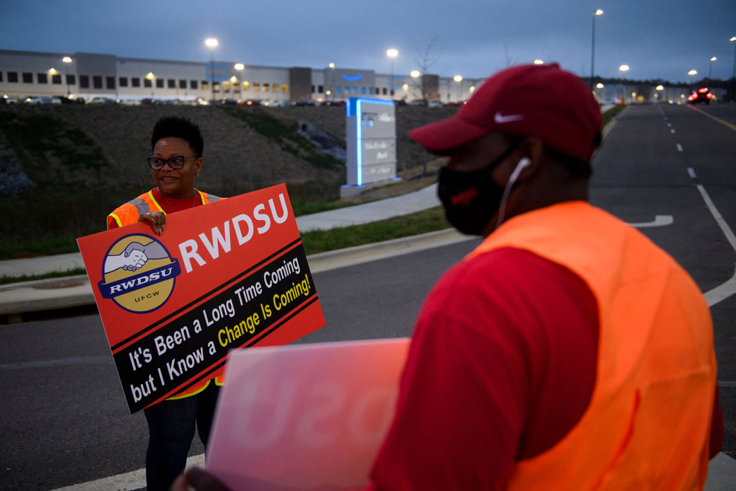 Union organizers wave to cars exiting an Amazon fulfillment center on March 27, 2021, in Bessemer, Alabama.