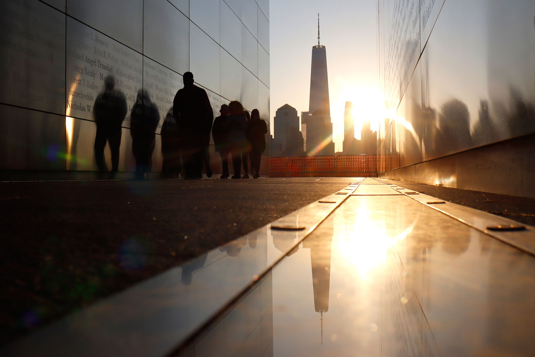 The sun rises behind the skyline of lower Manhattan and One World Trade Center in New York City as people walk through the Empty Sky 9/11 memorial in Jersey City, New Jersey, on April 24, 2021. (Getty/Gary Hershorn)