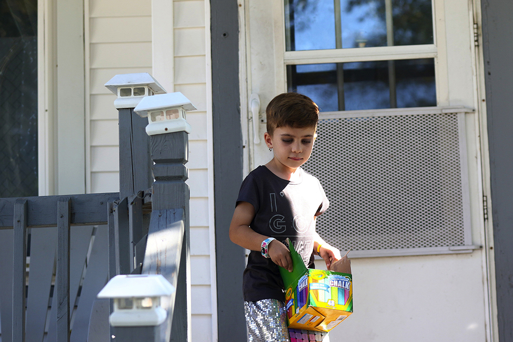 A young child carries a box of chalk outside their home, September 2018, in Milwaukee. They are one of a growing number of intersex children whose parents are raising them without early genital surgery. (Getty/John J. Kim/Chicago Tribune/Tribune News Service)