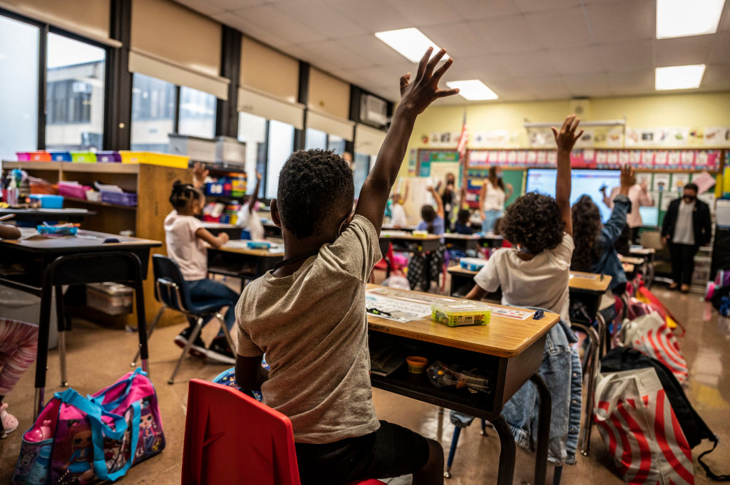 Child raises hand in class on first day of school