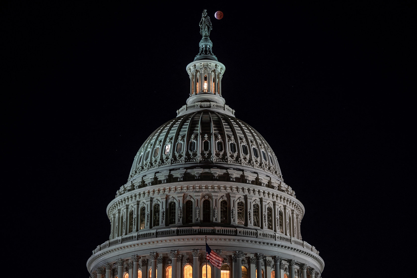 A partial lunar eclipse behind the dome of the Capitol building