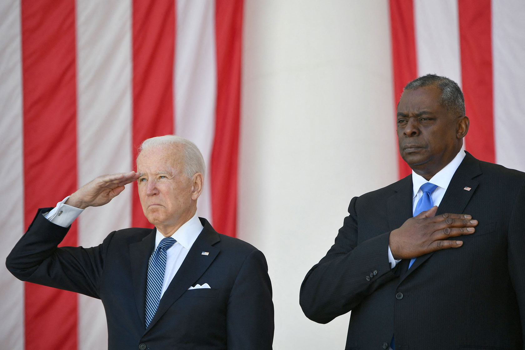 President Joe Biden salutes alongside Secretary of Defense Lloyd Austin before delivering an address at Arlington National Cemetery.
