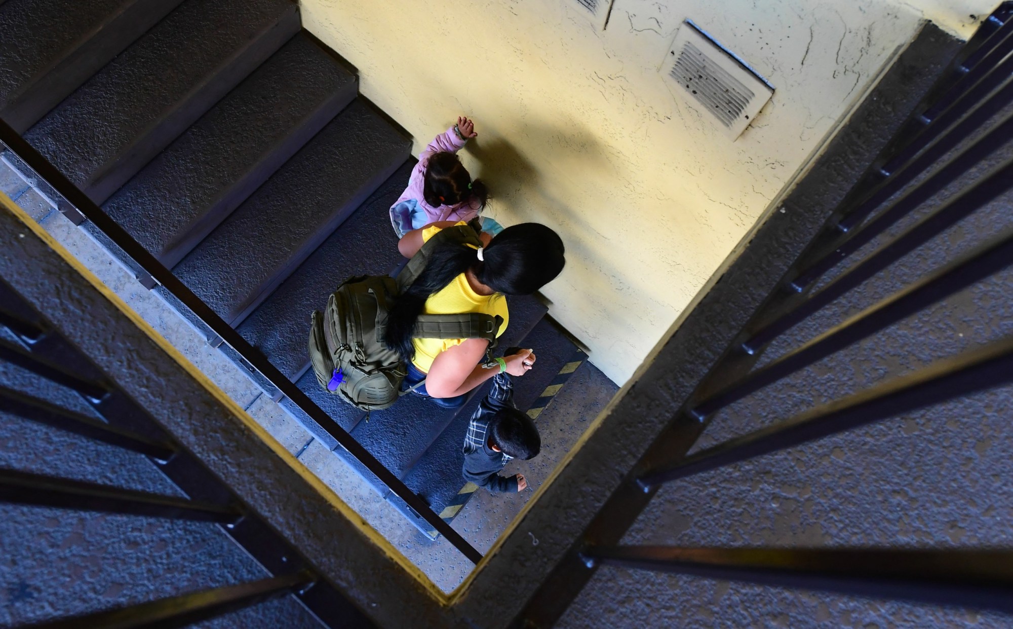 A mother and her two children walk down a flight of stairs at a shelter in San Diego.