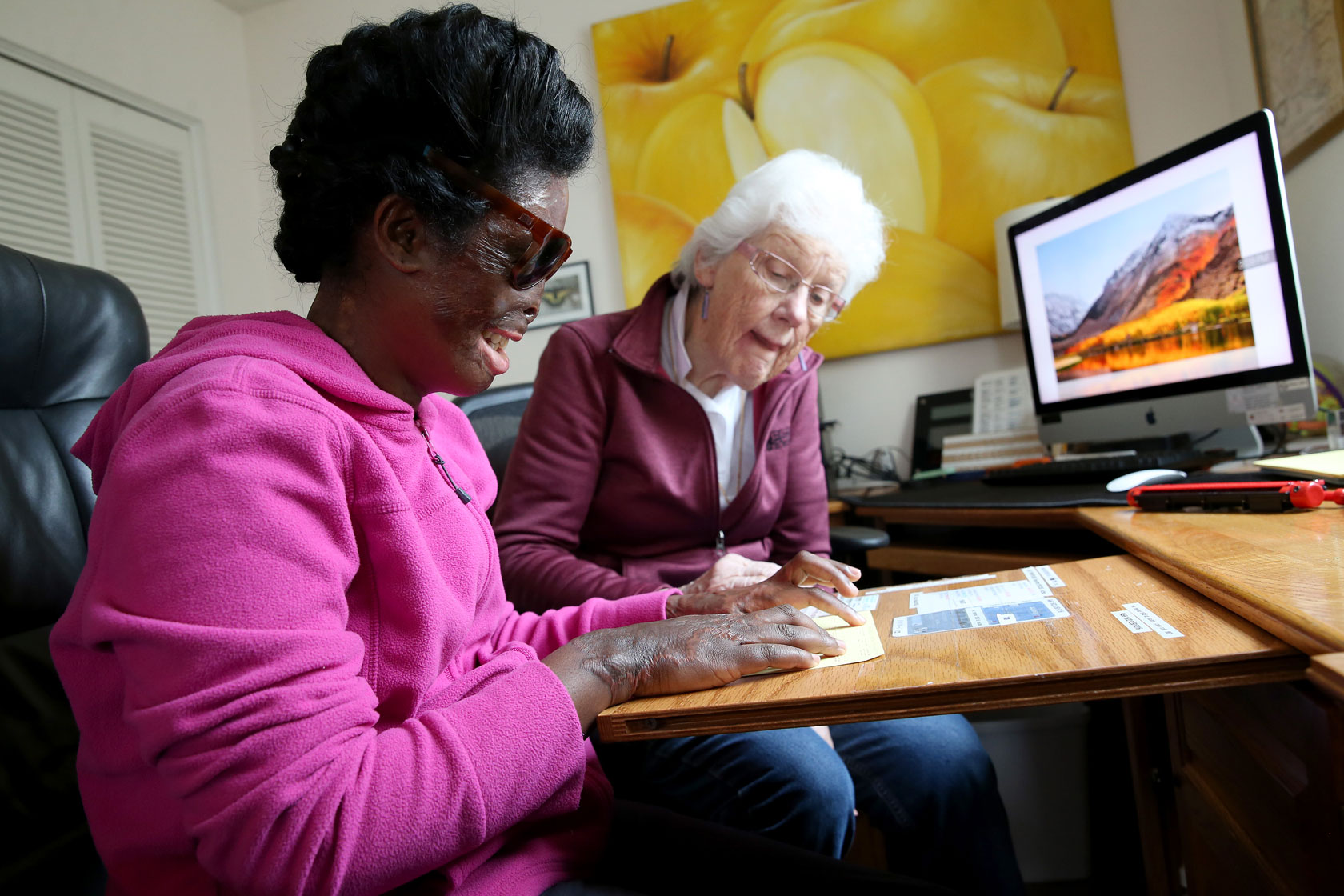 A woman, left, studies Braille with a volunteer teacher.