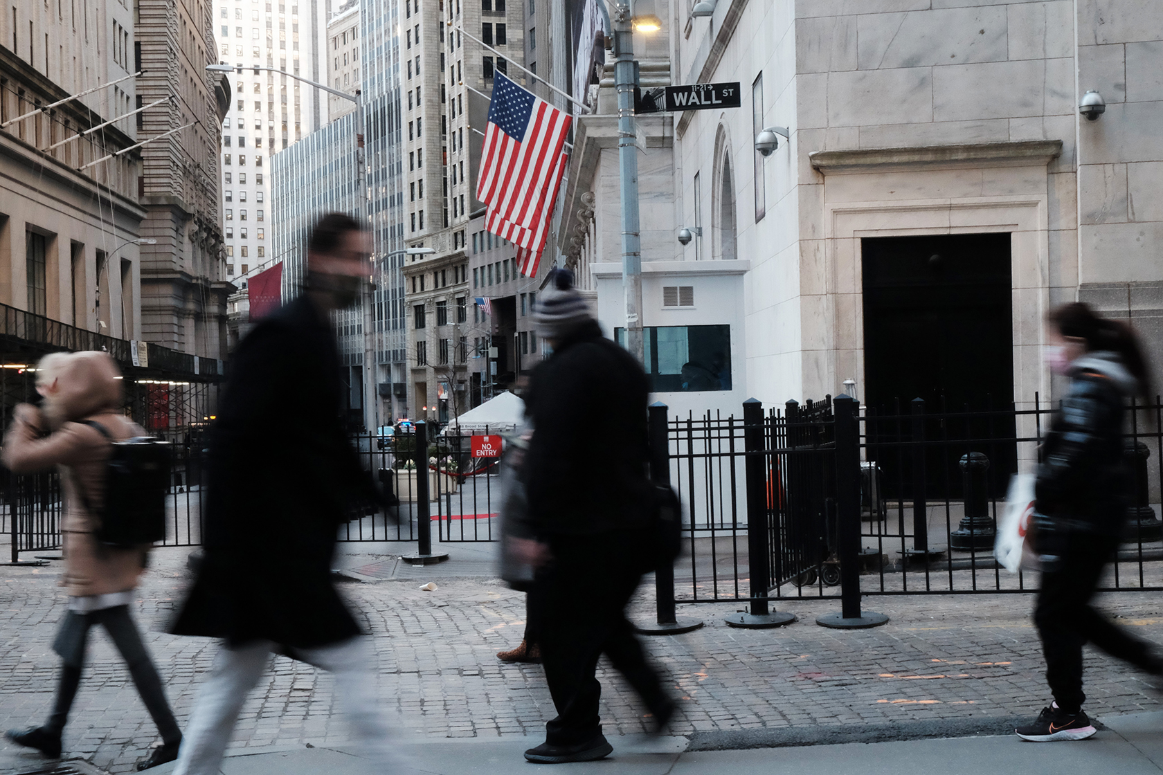 People walk under Wall Street street sign