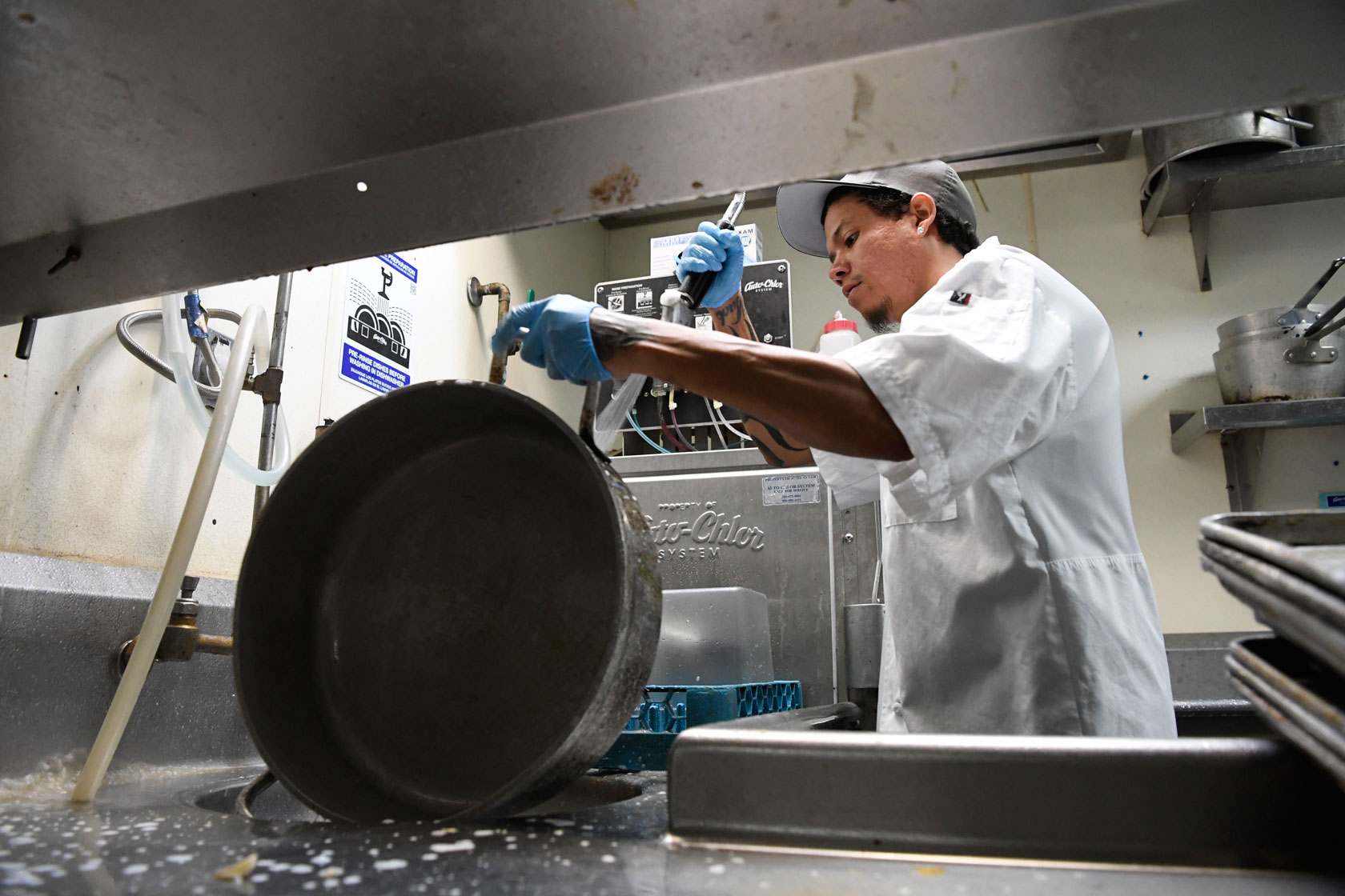 A dishwasher cleans a pot.