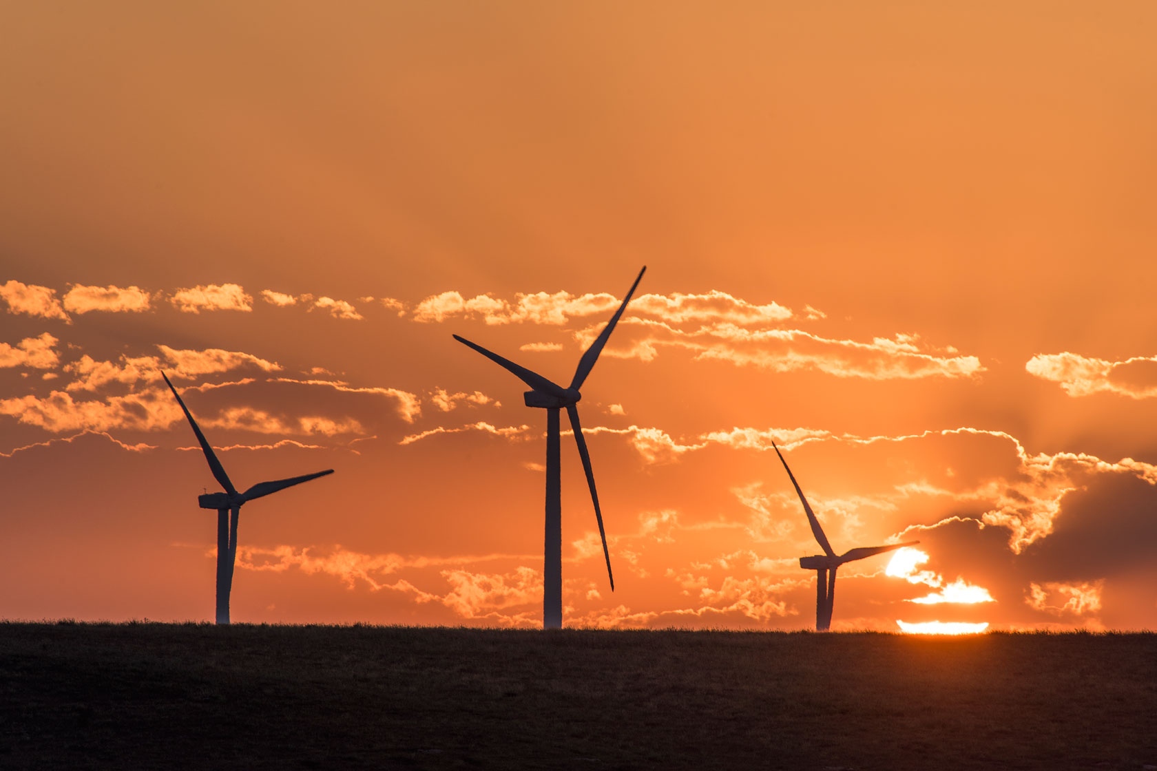 The sun sets over wind turbines.