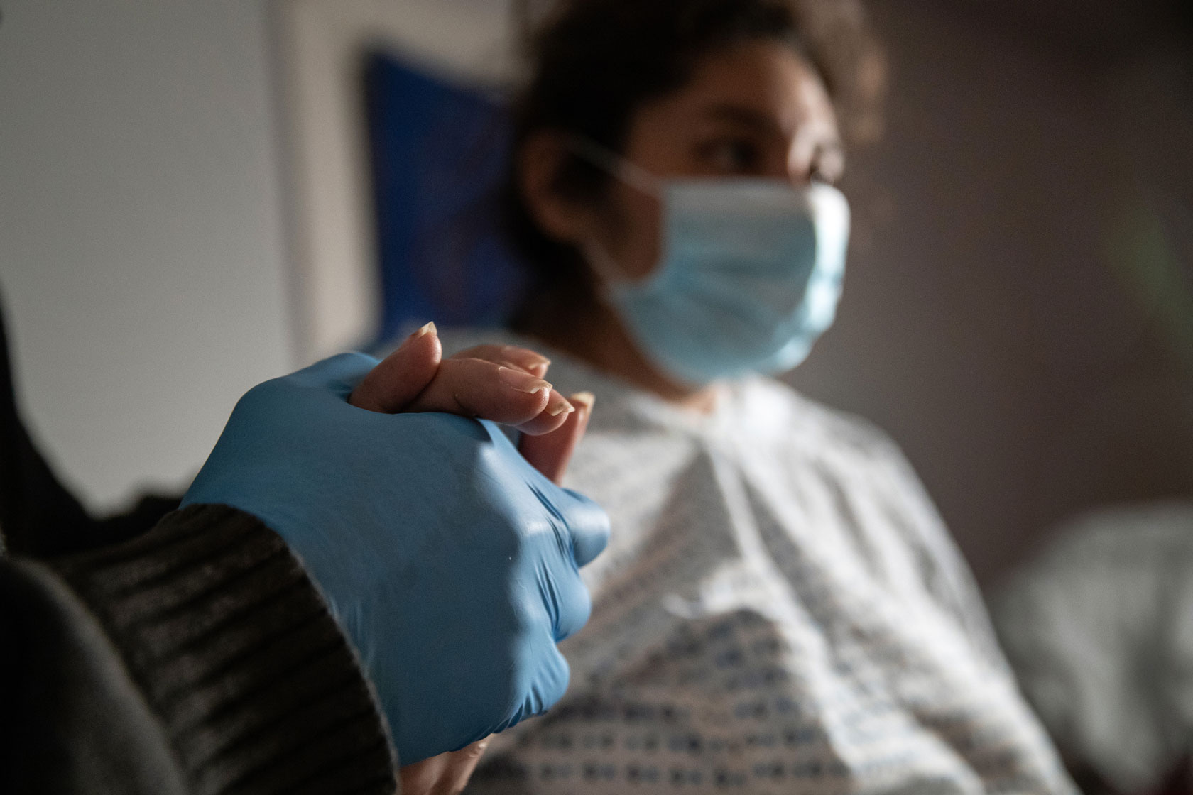 A man holds his wife's hand after she returns from the hospital, where doctors performed an emergency cesarean section.