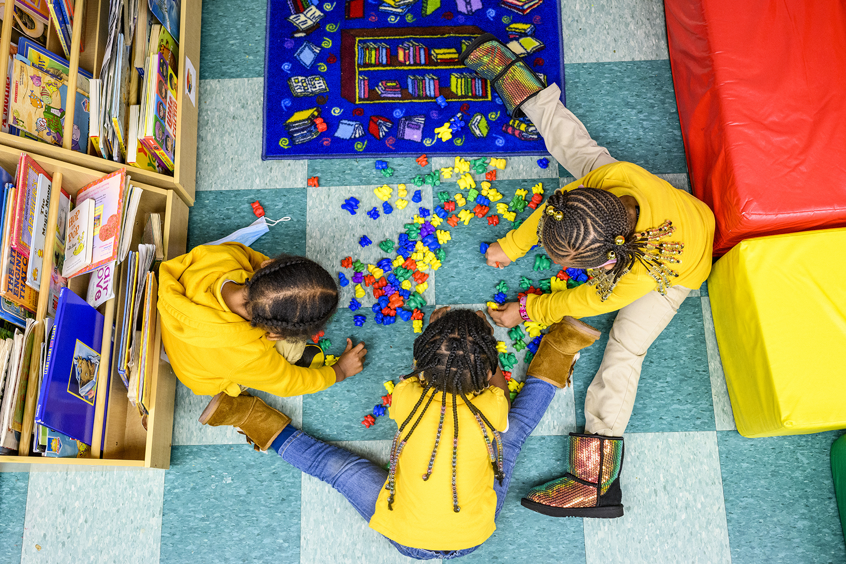 Three children playing with plastic toys seen from overhead