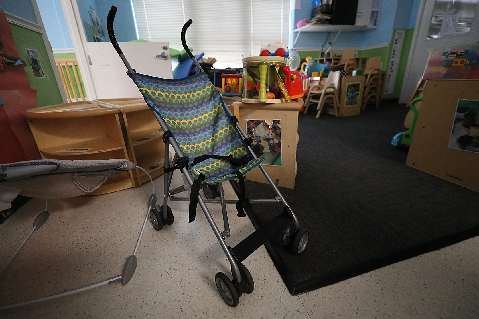 An empty child care room with a stroller in the foreground