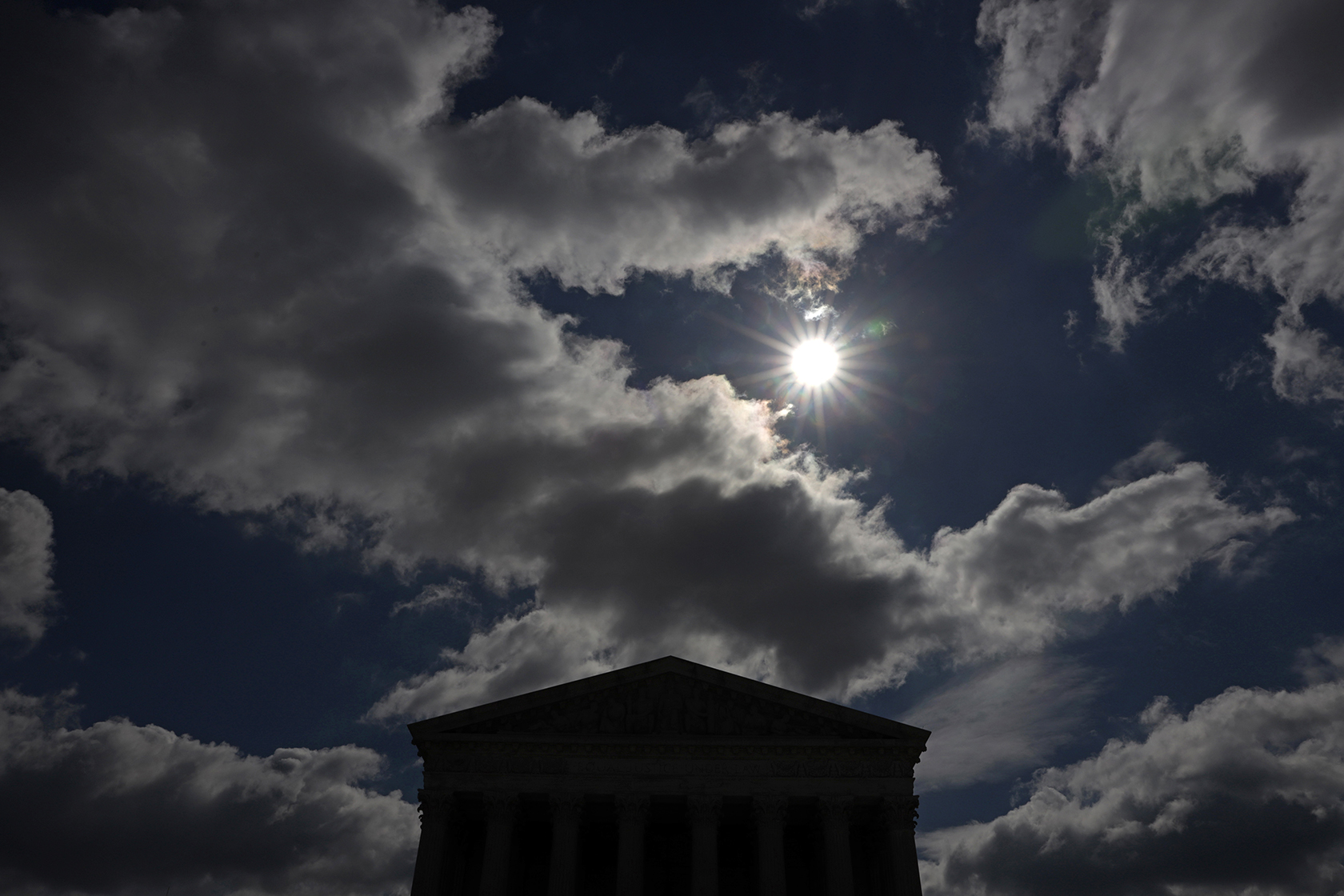 Clouds and sun in dark sky above Supreme Court building