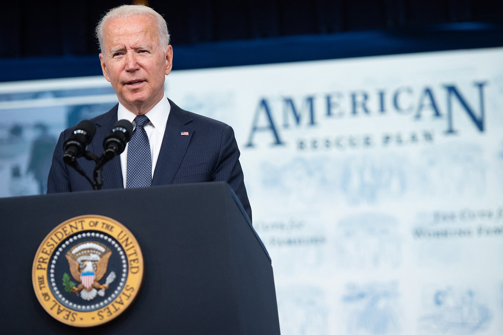 Joe Biden behind podium and in front of sign that reads American Rescue Plan