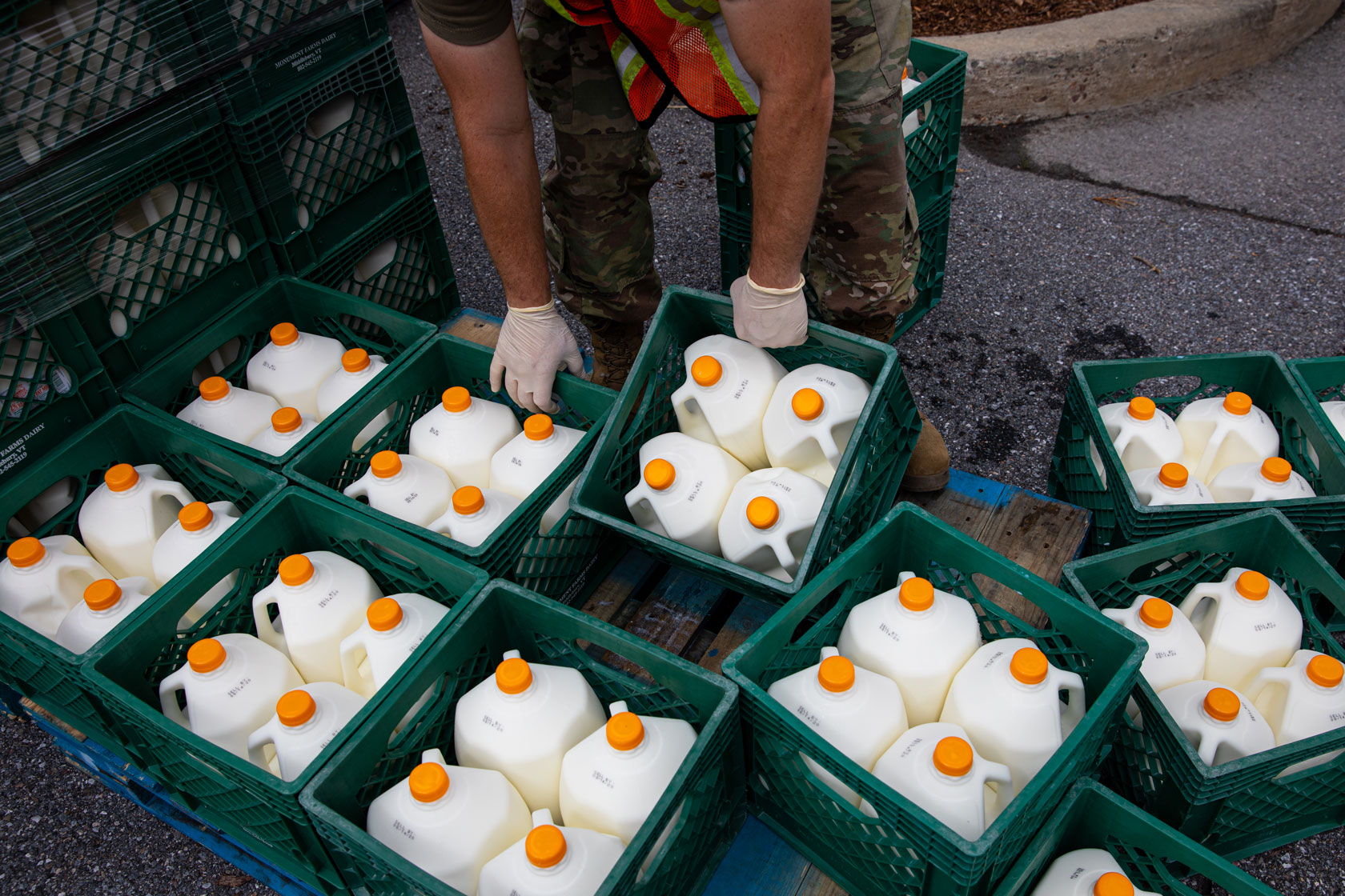 A member of the Vermont National Guard loads bins of milk into a car.