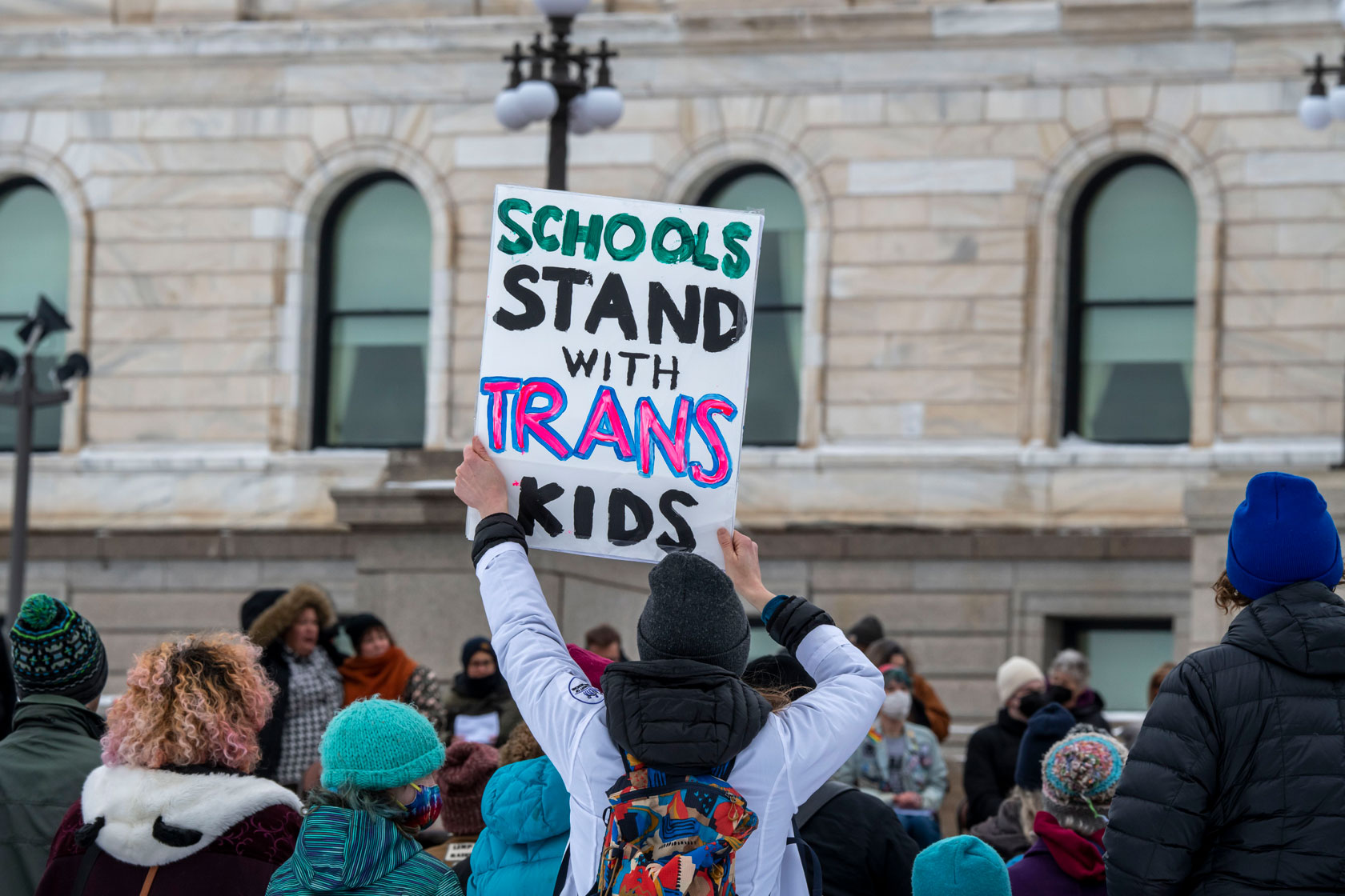 A protestor in front of the Minnesota capitol holds a sign reading 