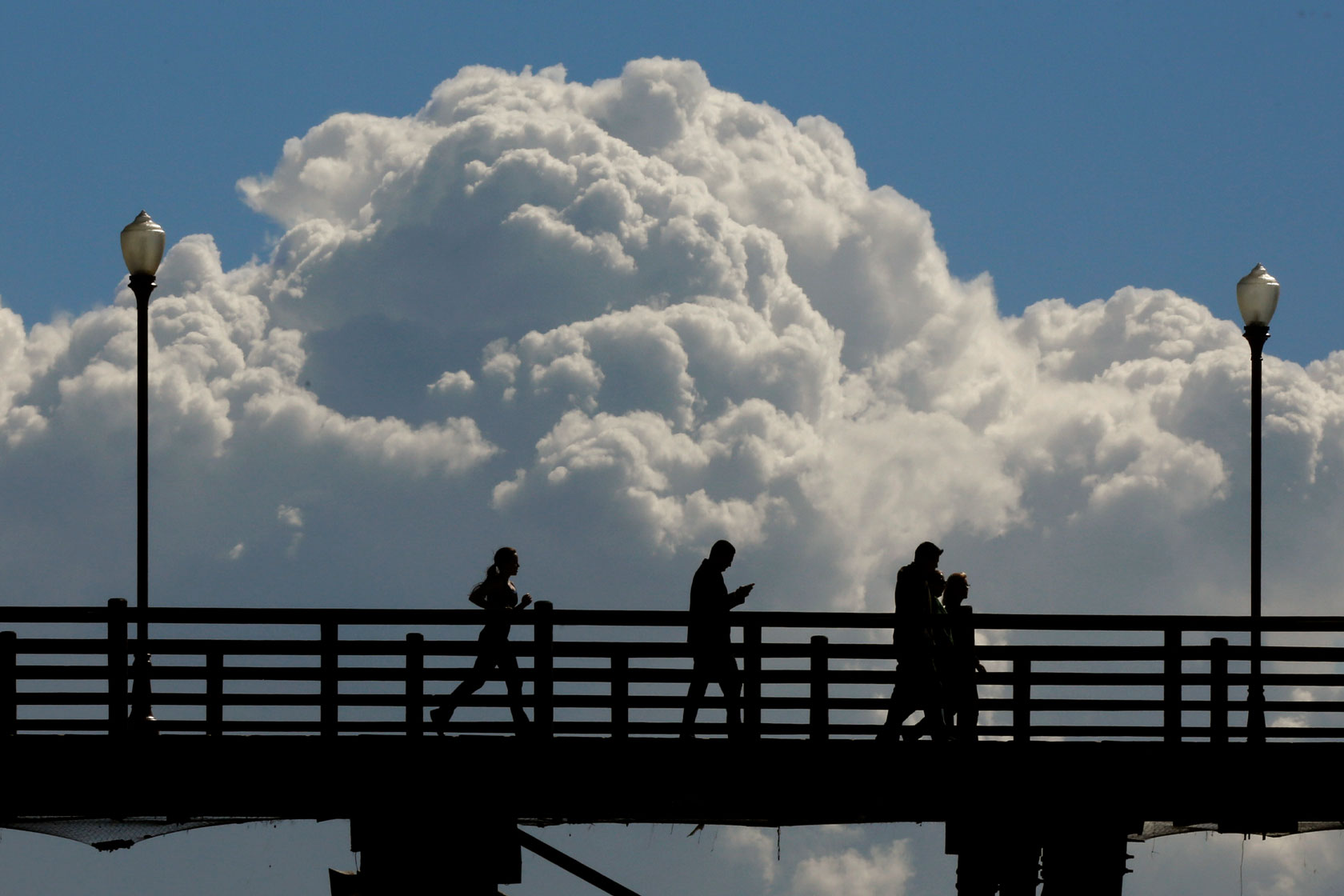 People jog and walk across the Oceanside Pier.