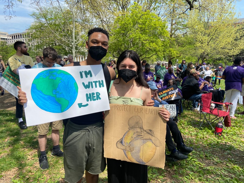 Kamari Smith (left) holds a sign picturing the planet Earth that reads: 