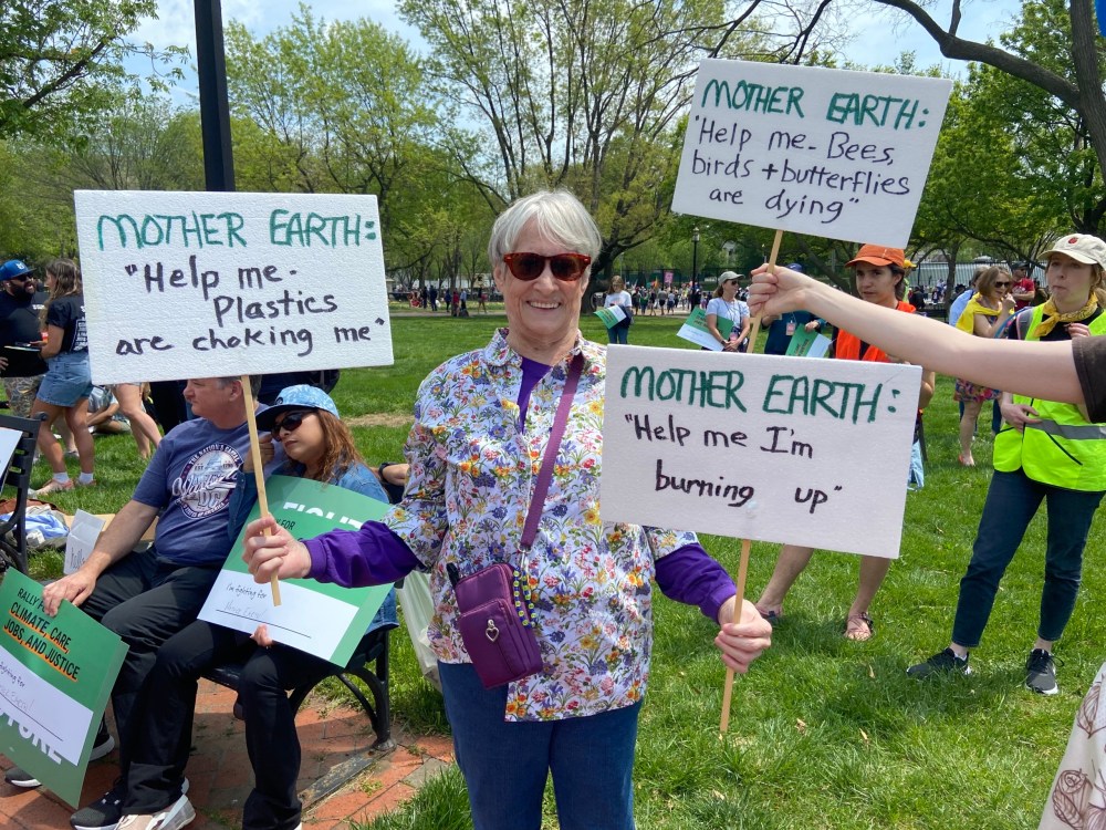 Kathy Mikesell holds three signs that urge us to