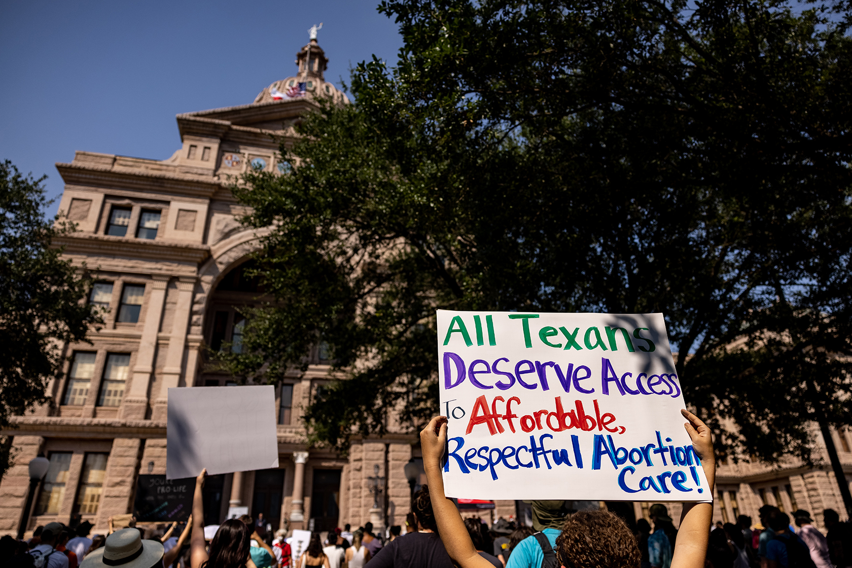 Protestor holding sign that says all Texans deserve access to affordable, respectful abortion care