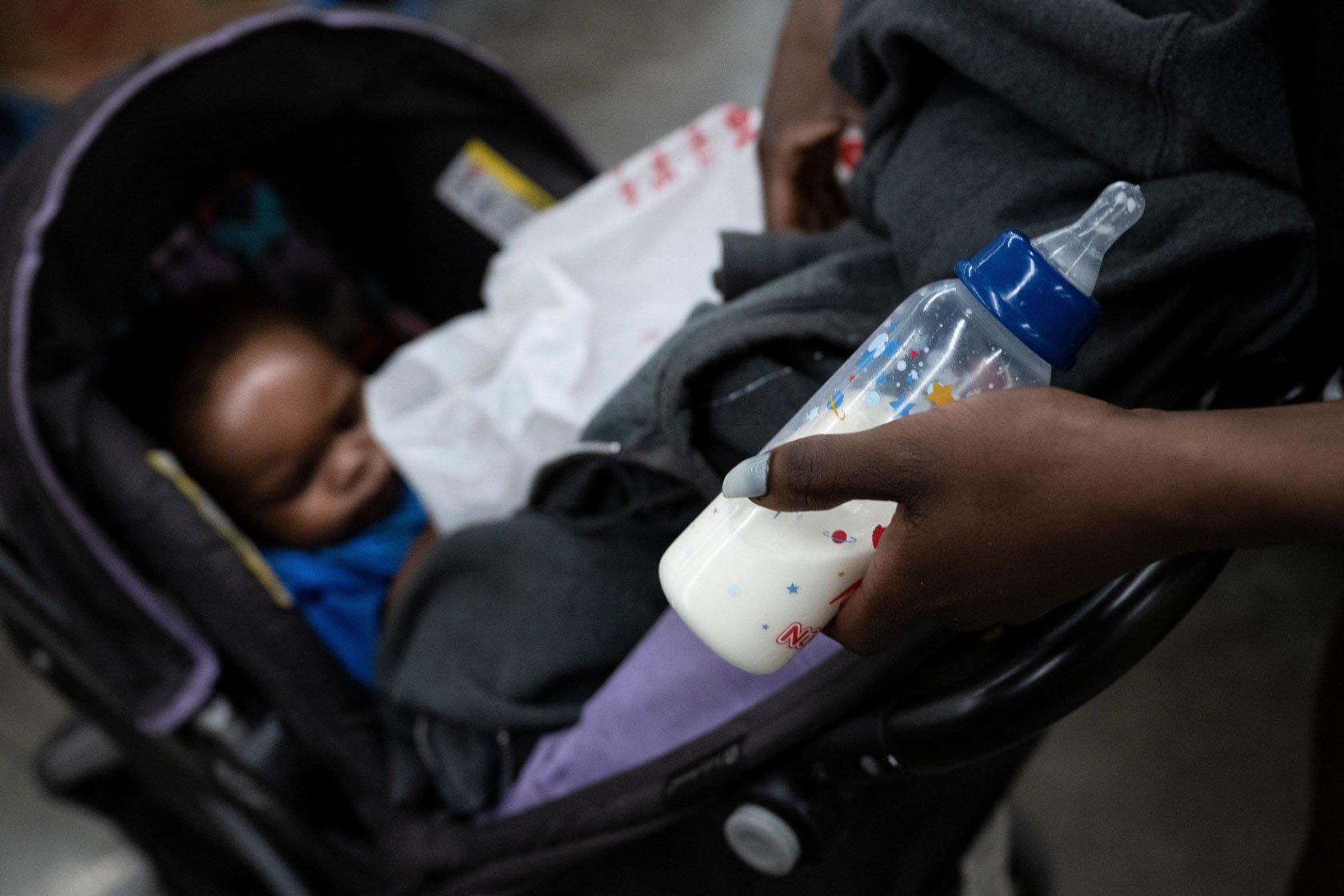 A mother holding a bottle of formula visits a grocery store in Washington, D.C., with her son to look for baby formula during the U.S. shortage.