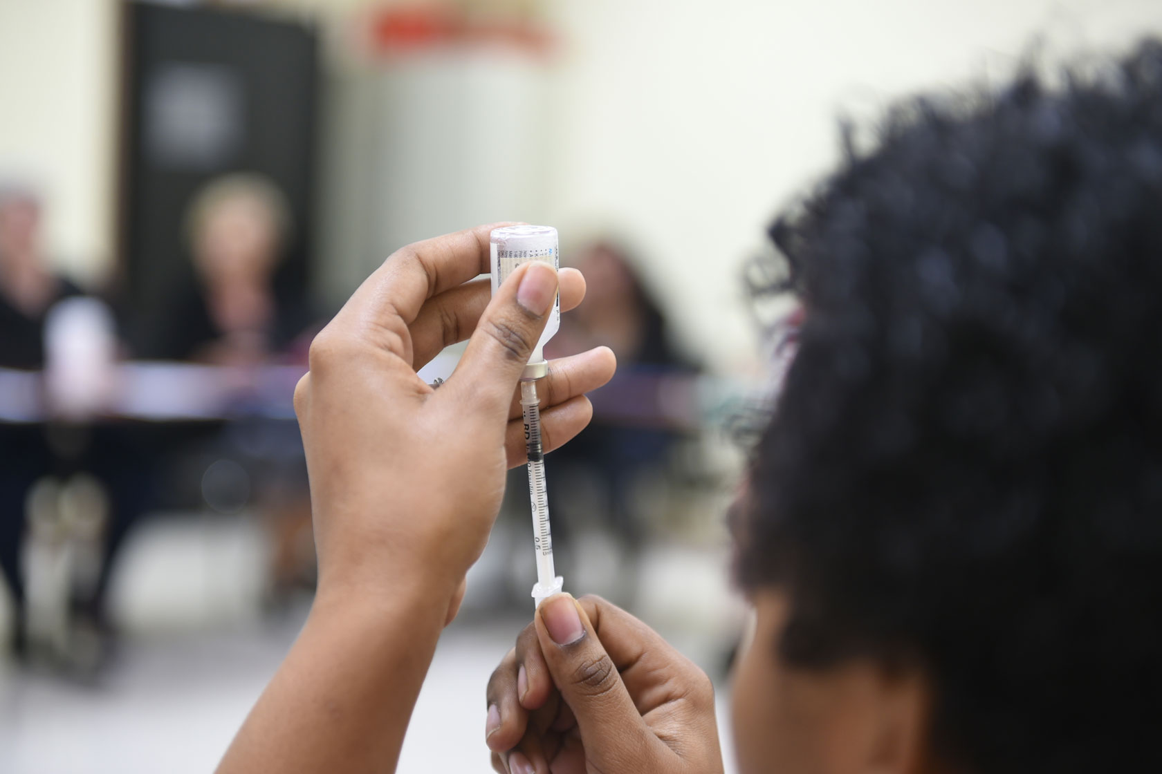 A woman holding a syringe educates health care workers on administering insulin.