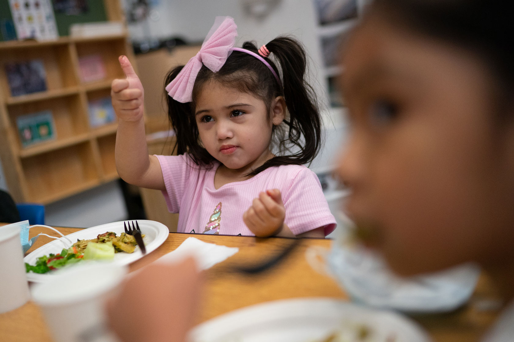 A young student gives a thumbs up when asked about her healthy lunch.