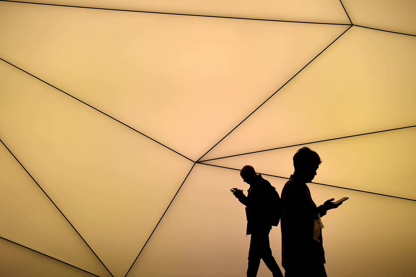 Two people in shadow looking down at their phones