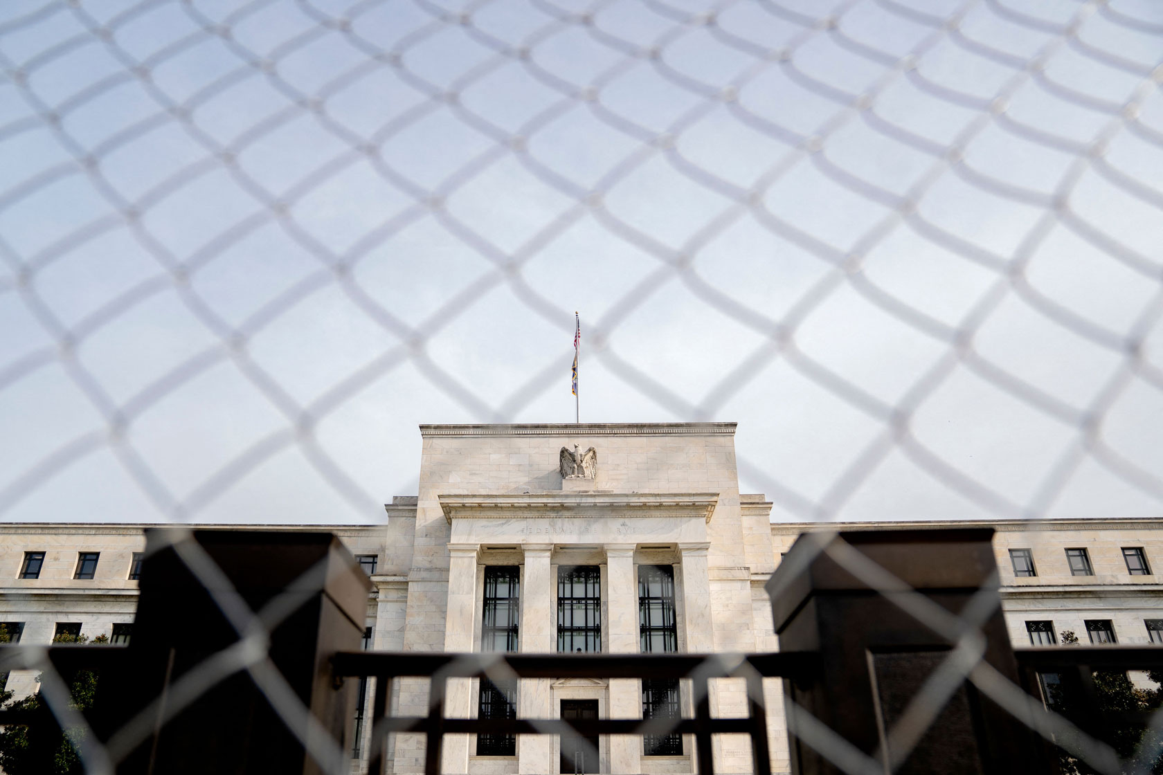 Photo shows the Federal Reserve building through fencing.