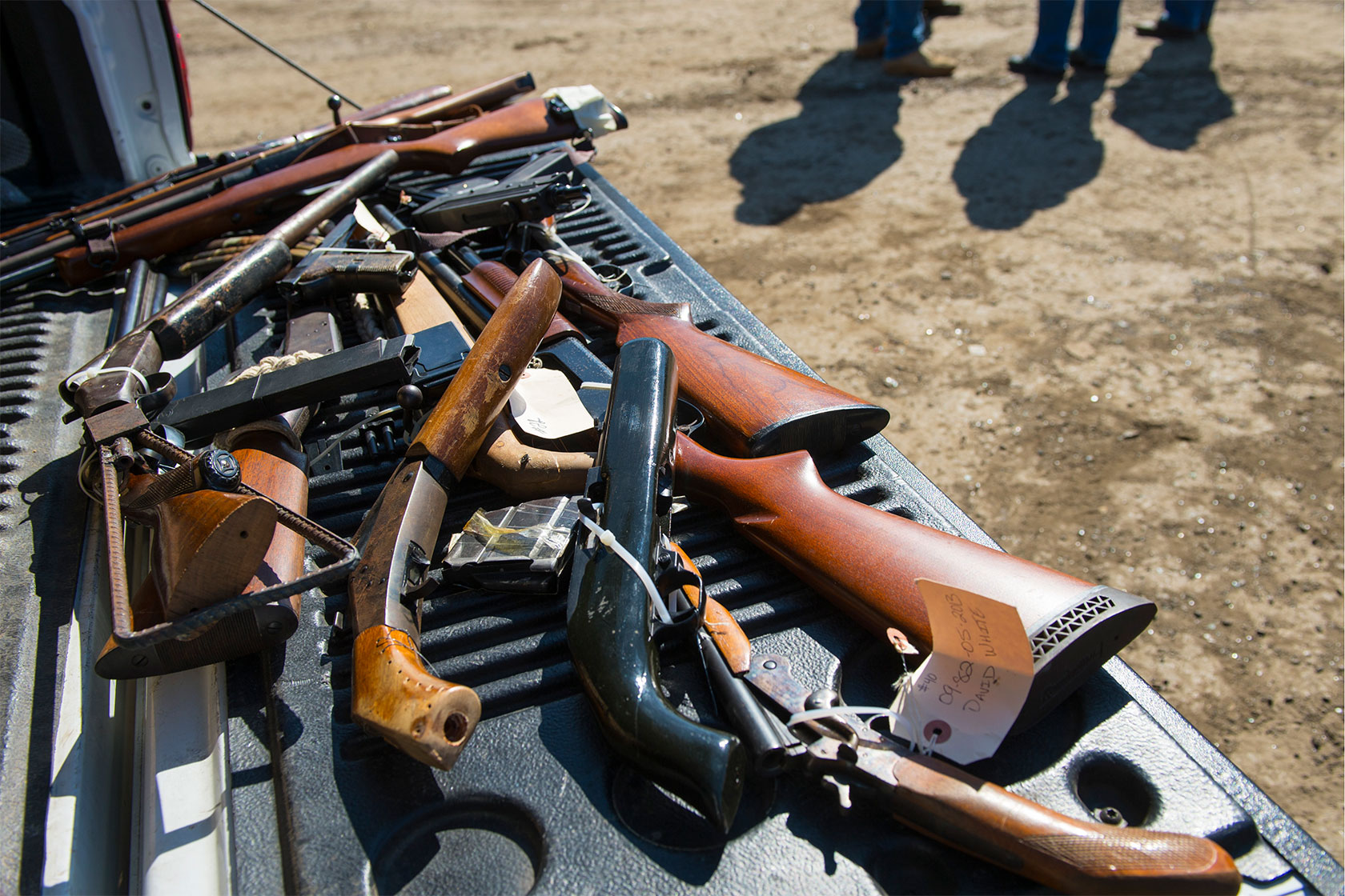 ATF agents are seen in shadows next to a pickup truck bed holding seized and purchased guns in Maryland.