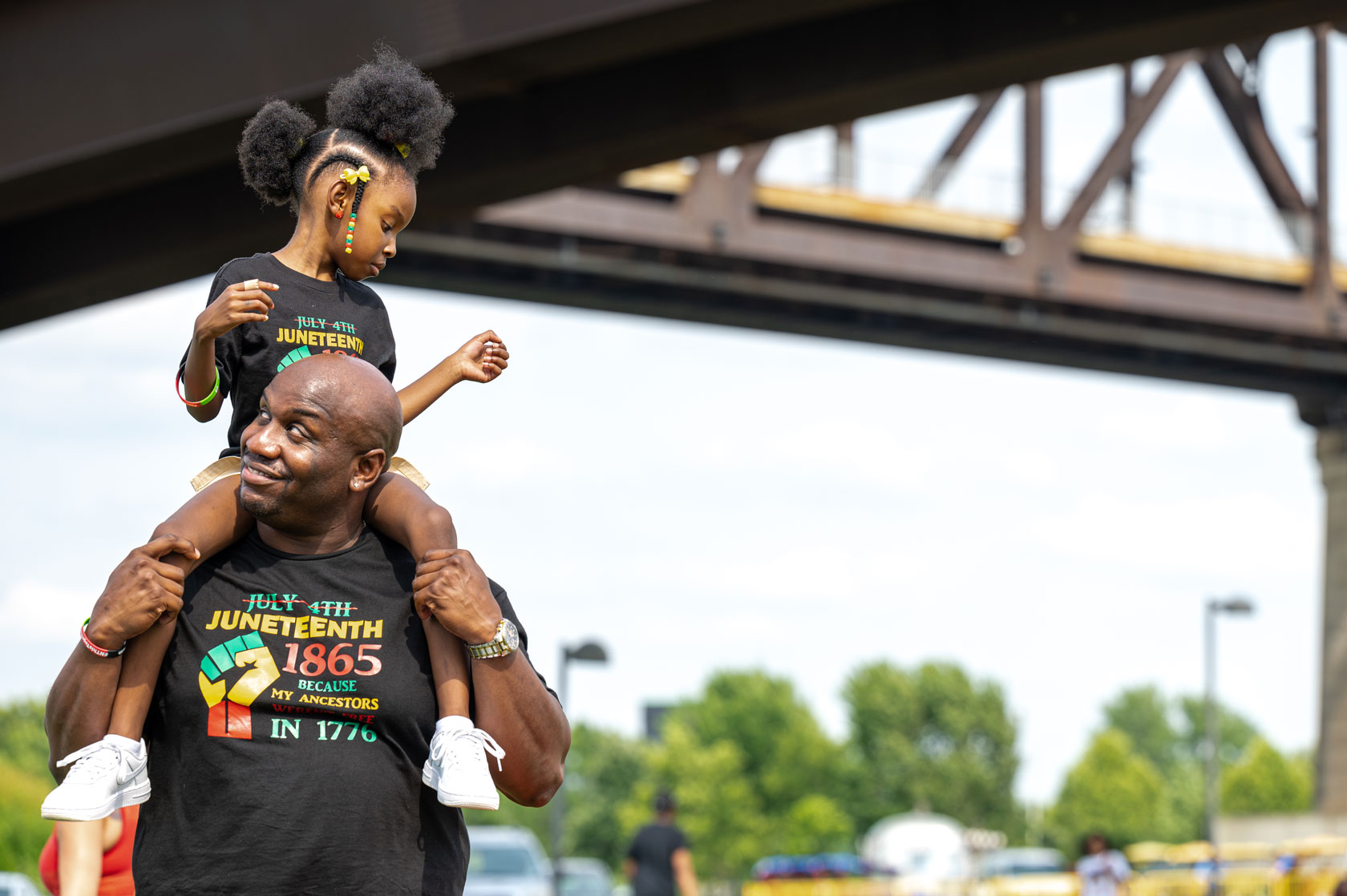 A young girl sits on a man's shoulders during the Louisville Juneteenth Festival.