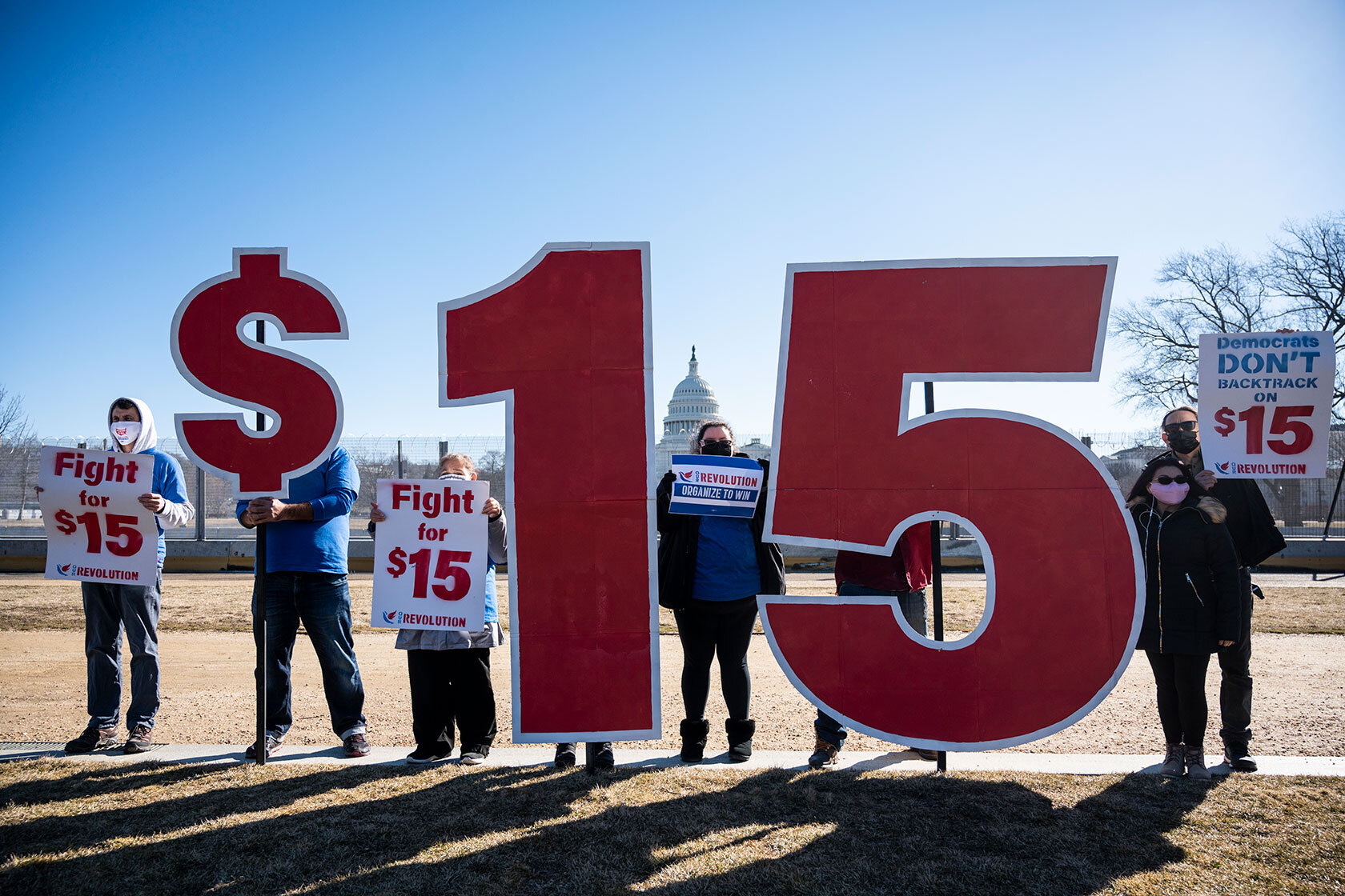 Activists with Our Revolution hold $15 minimum wage signs outside the U.S. Capitol.
