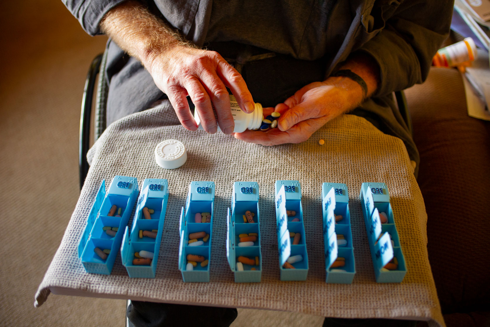 A person who has multiple sclerosis sorts his medication into a pill organizer.