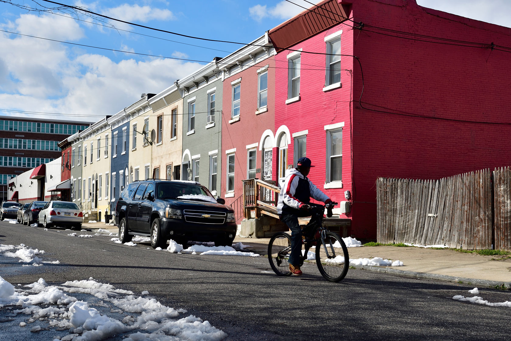 A man bicycles past a row of houses in Philadelphia.
