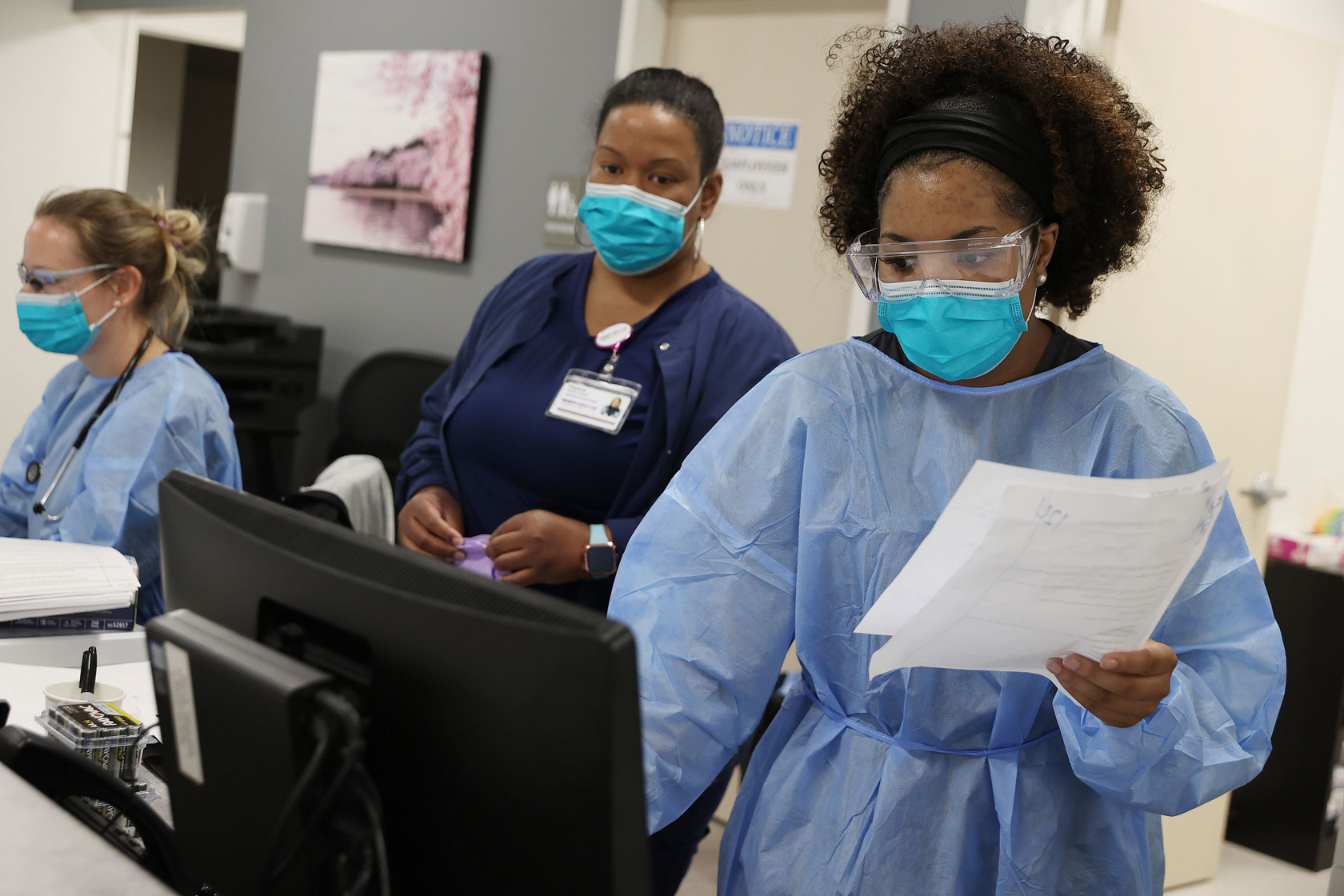 Health care workers at an urgent care center in Woodbridge, Virginia, handle careful patient records in front of a computer.