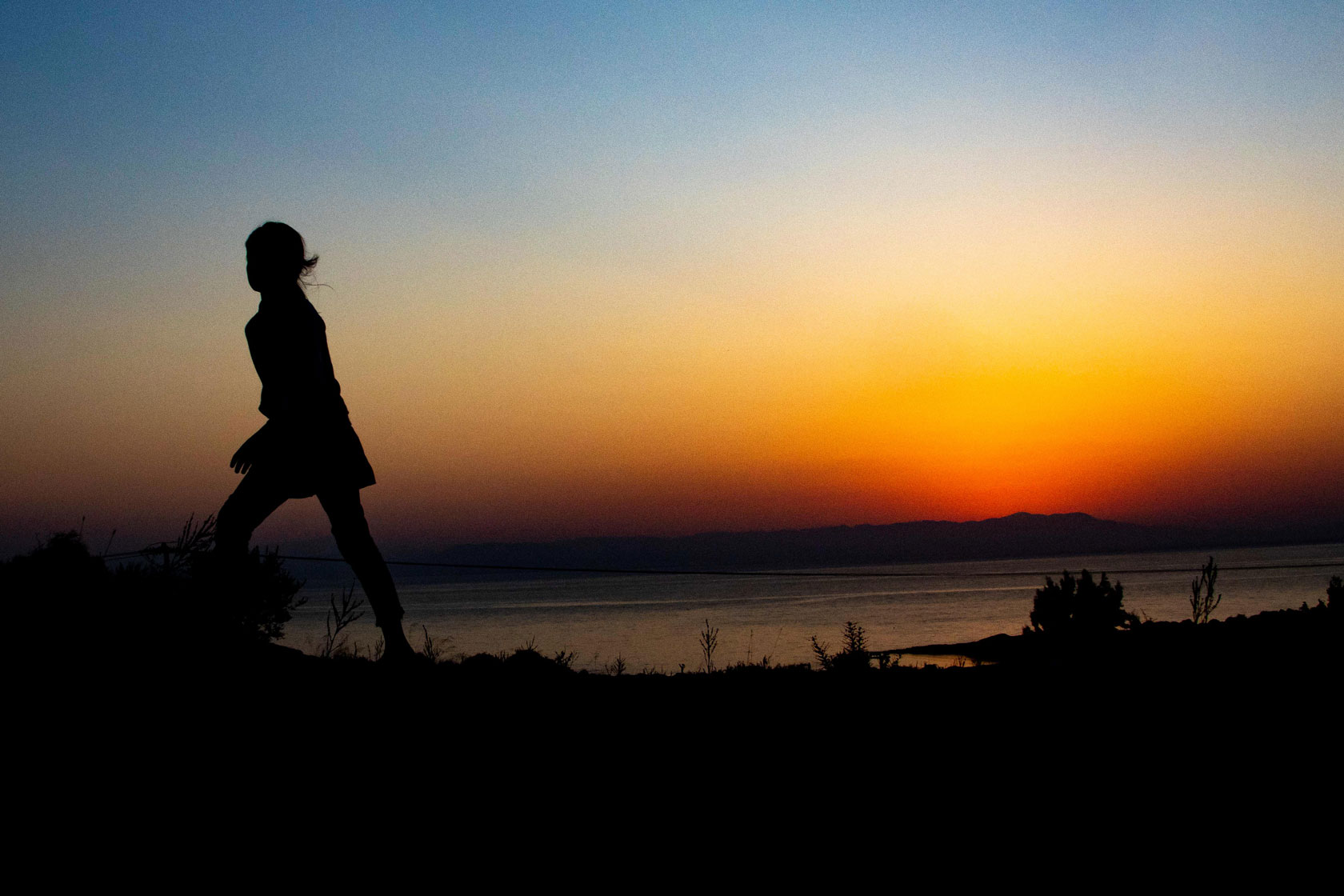 The silhouette of a girl walking as the sun rises