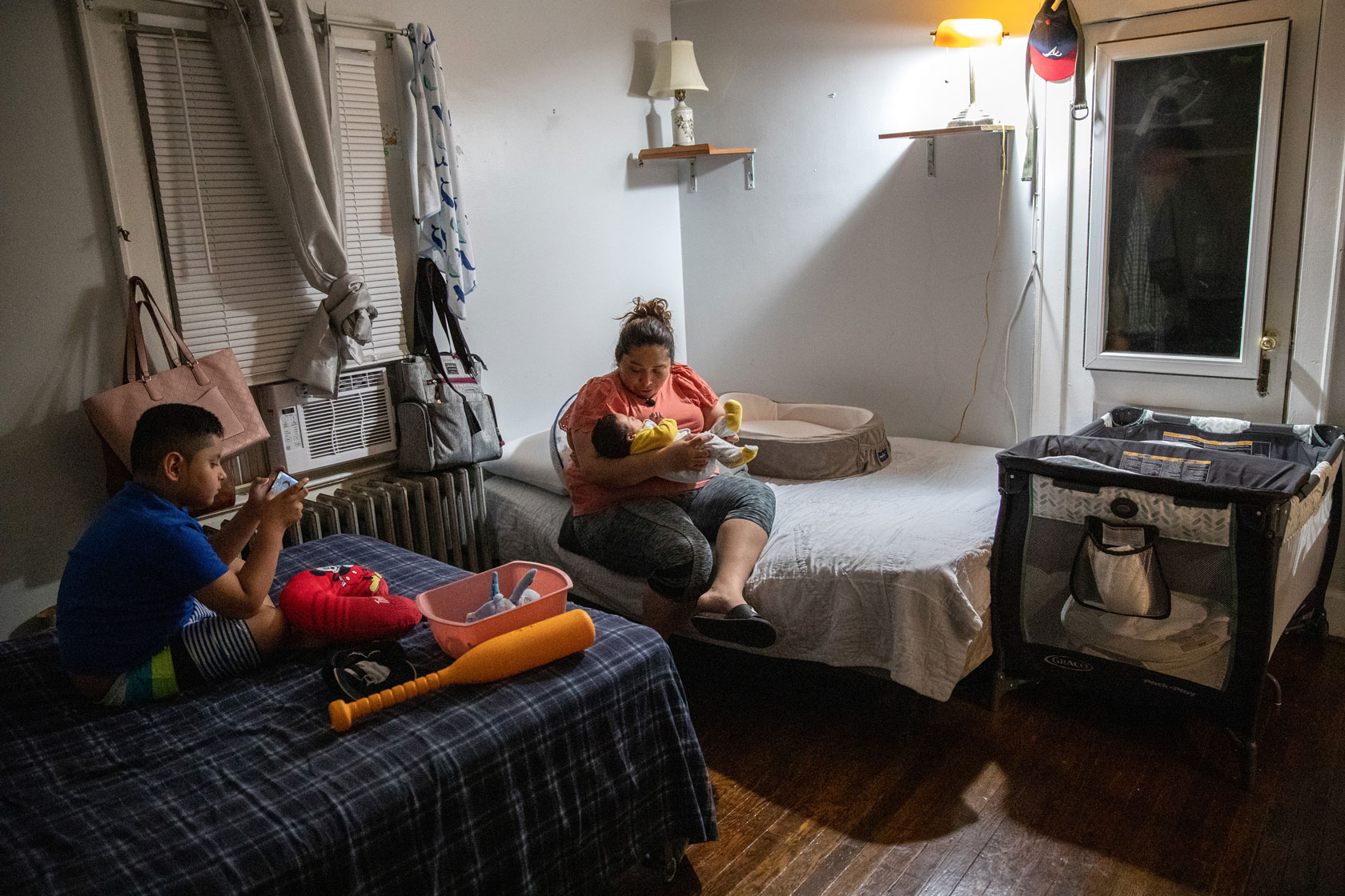 A mother prepares her 10-week-old son for bed as her other child sits close by.