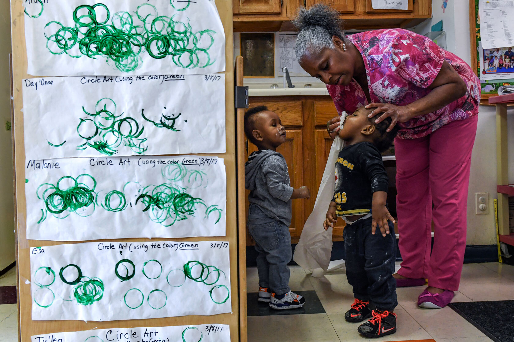 A child care worker cleans the face of a toddler at a learning center in Washington, D.C.,