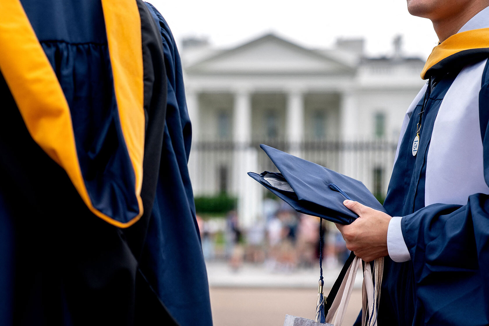 Students wear their graduation gowns outside of the White House.