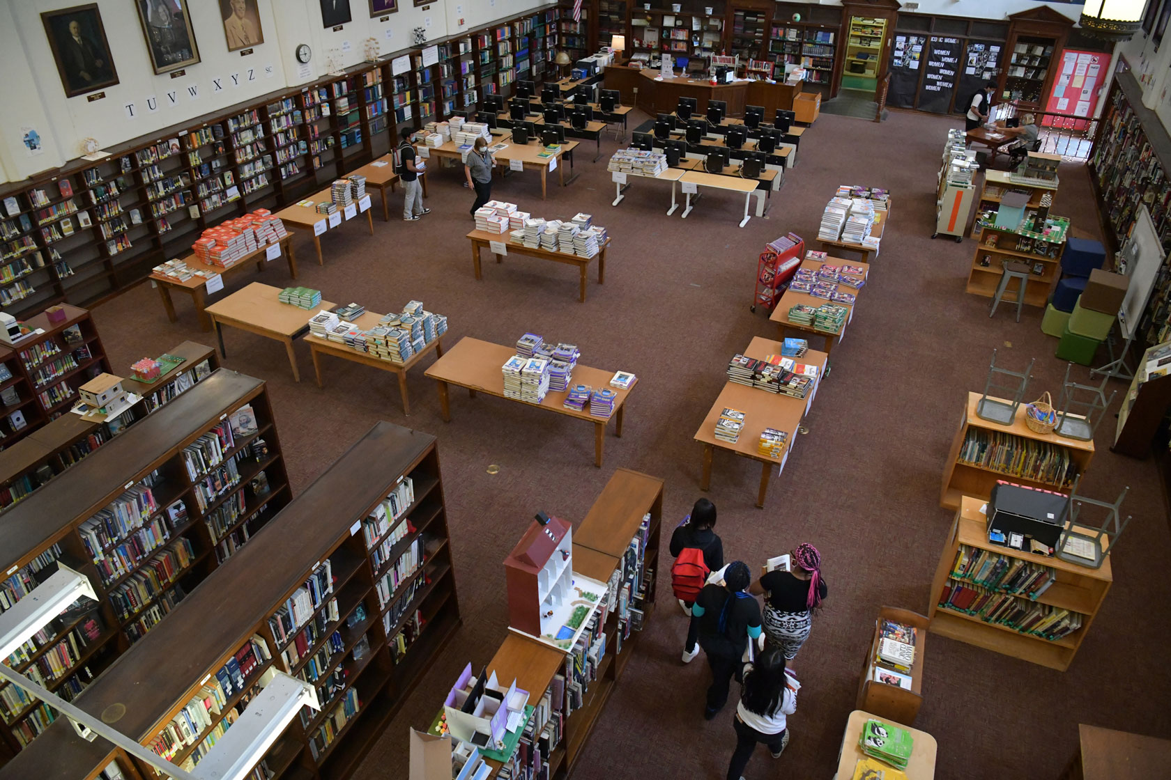 Photo shows an aerial view of a small group of students entering a library in a high school