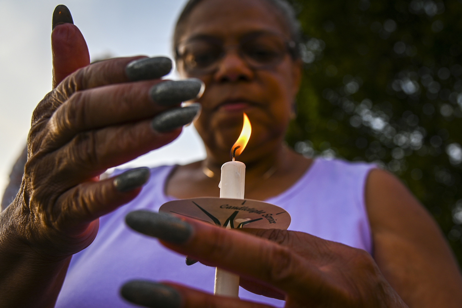 Woman in close-up shielding candle flame with hand