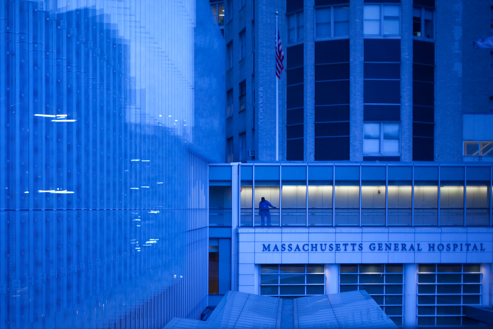 A man stands in a walkway above a sign that reads, 