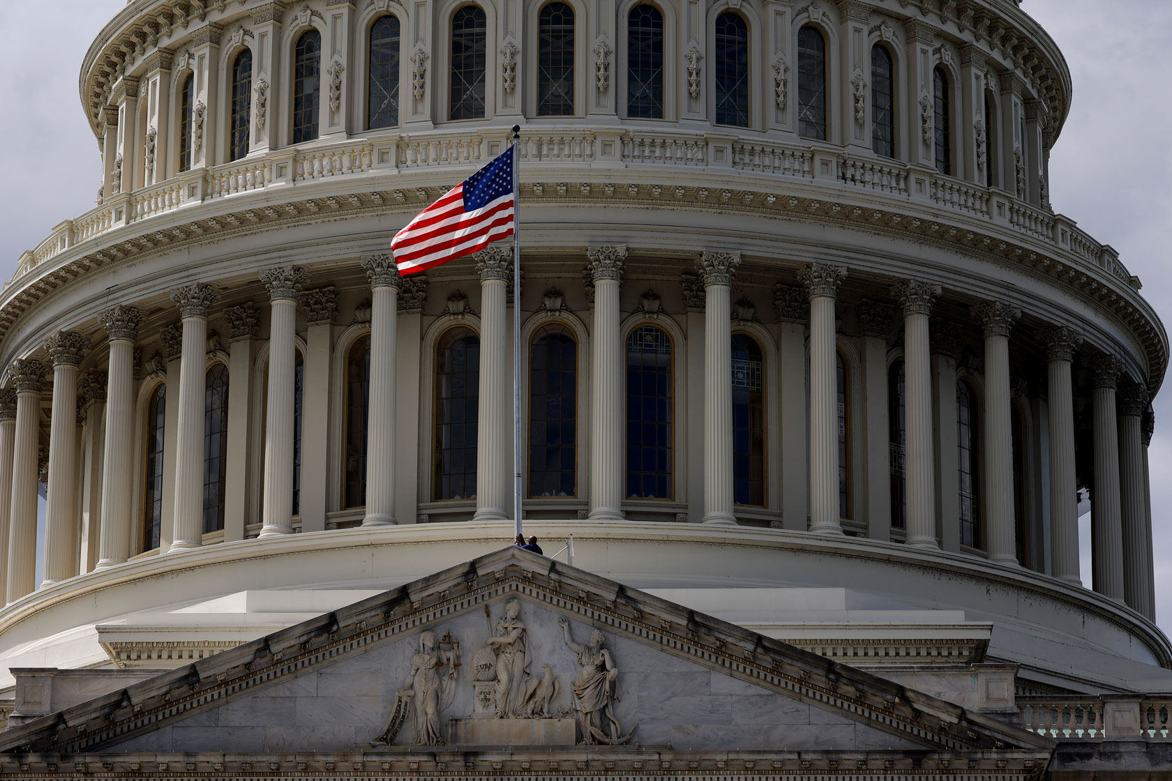 Photo shows a close-up view of the U.S. Capitol building with the American flag in the foreground.