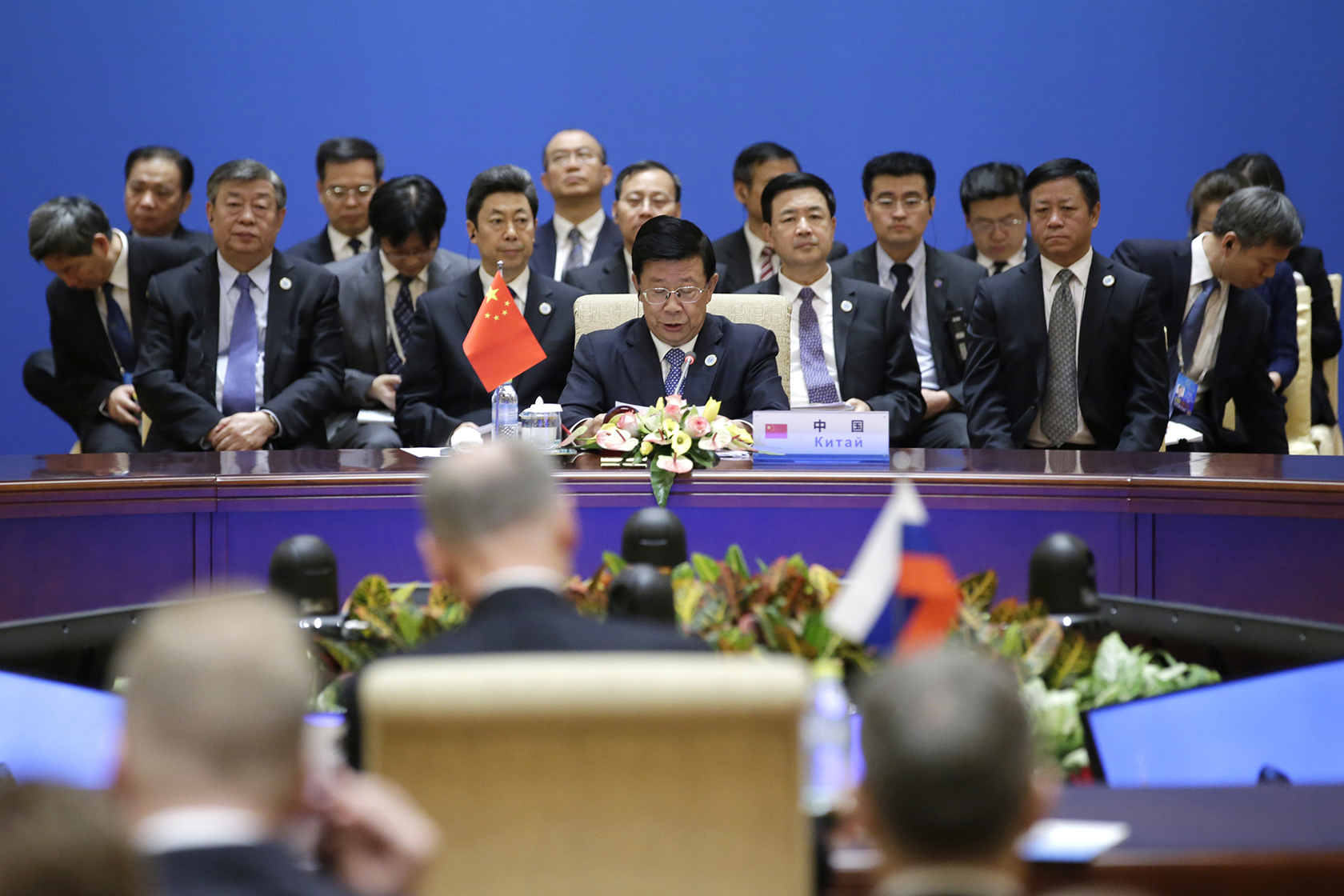 Zhao Kezhi seated behind table surrounded by attendees