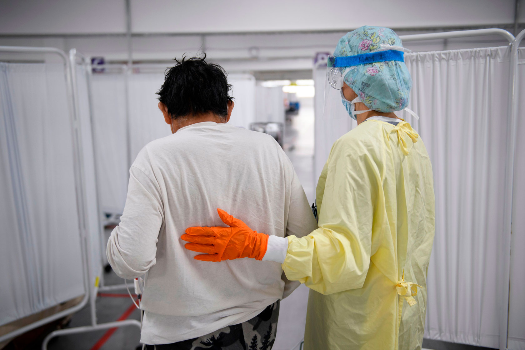 Photo shows a nurse walking with a patient.