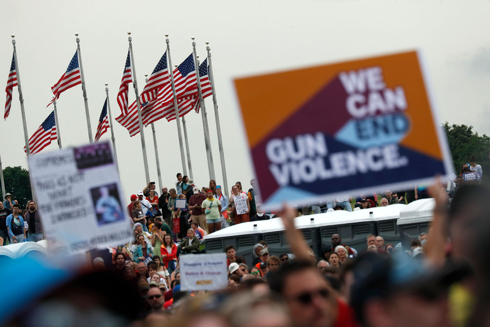 A crowd is gathered to protest gun violence, with one sign that says, 