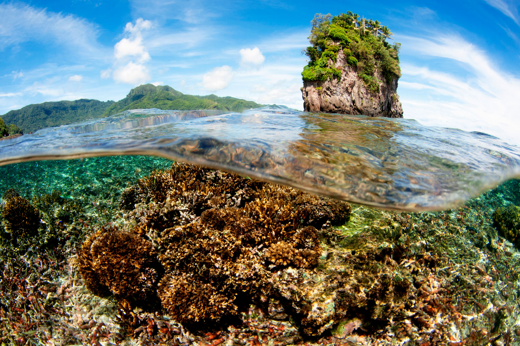 A shallow coral head appears in front of Fatu Rock.