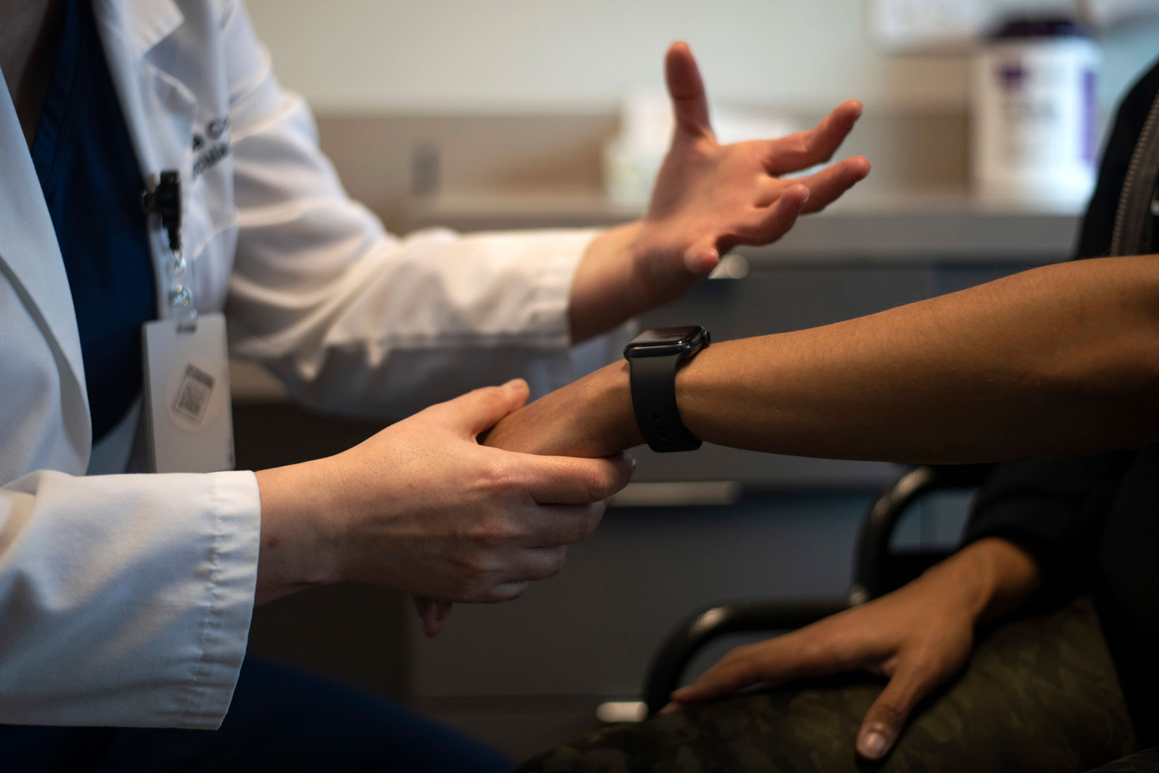 A doctor holds a patients hand during an appointment.