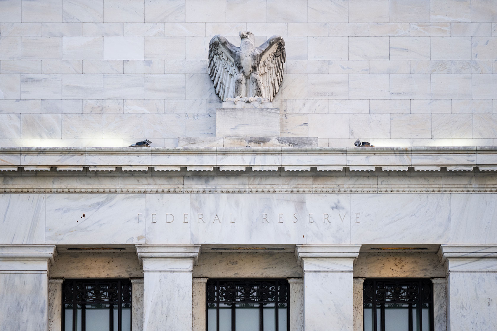 Photo shows the marble facade of the Federal Reserve, with the sculpture of an eagle at center.