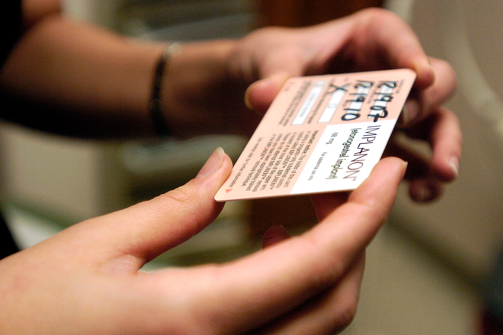 A woman reads a reminder and expiration card for a contraceptive implant.